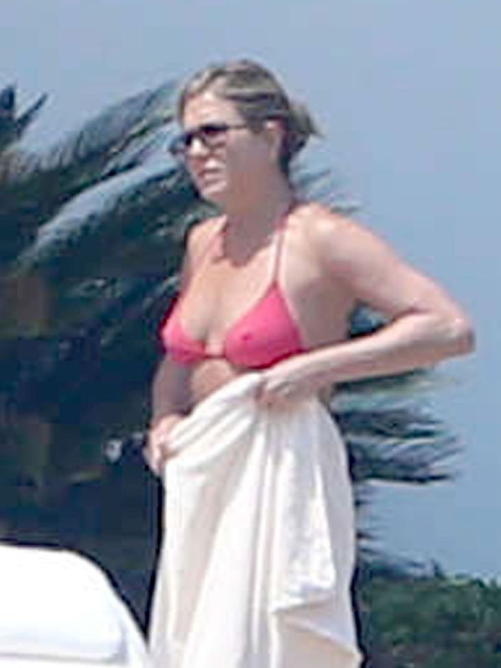 Jennifer Aniston skjuler sin mave med håndklædet men viser sin flotte overkrop frem. (Foto: All Over Press)