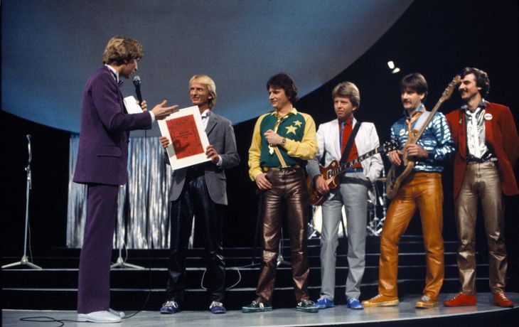 Jørgen de Mylius har overrakt Jens Brixtofte det synlige bevis på, at han sammen med sin gruppe, Brixx, har vundet det danske Melodi Grand Prix i 1982 med sangen 'Video Video'. Foto: Polfoto