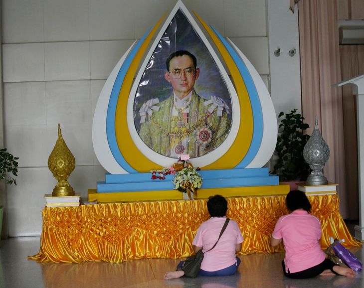 Thaier beder foran et portræt af den nu afdøde konge. Foto: AP
