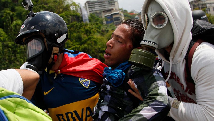 En såret demonstrant hjælpes væk efter en gadekamp med politiet i Caracas. (Foto: AP)
