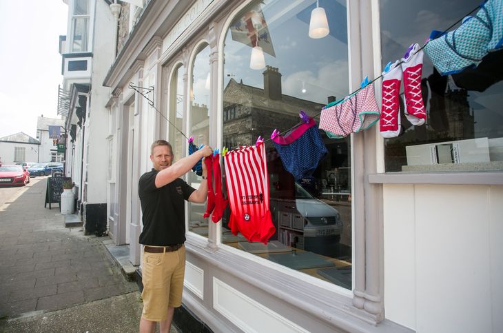 En butiksejer hænger vasketøj op foran sin forretning på hovedgaden i byen. (Foto: Ritzau/Scanpix)