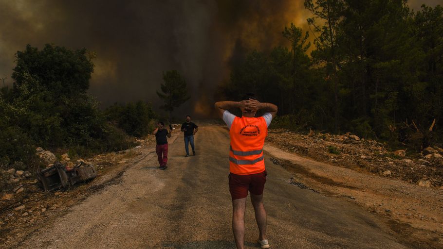 Folk på vild flugt fra en skovbrand nær den tyrkiske landsby Sirtkoy øst for Antalya ved Tyrkiets sydlige middelhavskyst. To personer i området mistede søndag livet i branden. Foto: Uncredited/Ritzau Scanpix