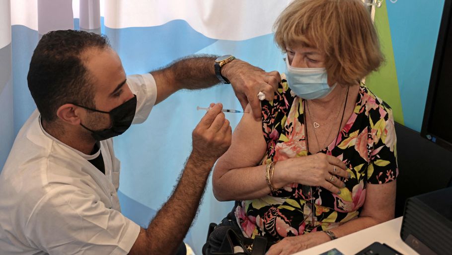 En israelsk sundhedsmedarbejder giver søndag det tredje stik med en coronavaccine til en borger over 60 år. I alt er der blevet givet knap en kvart million tredje vaccinedoser i Israel. Foto: Menahem Kahana/Ritzau Scanpix