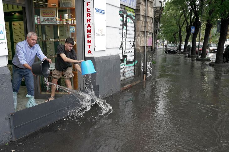 To mænd forsøger at holde regnvandet væk fra en butik i byen Catania på Sicilien tirsdag. Foto: Antonio Parrinello/Reuters