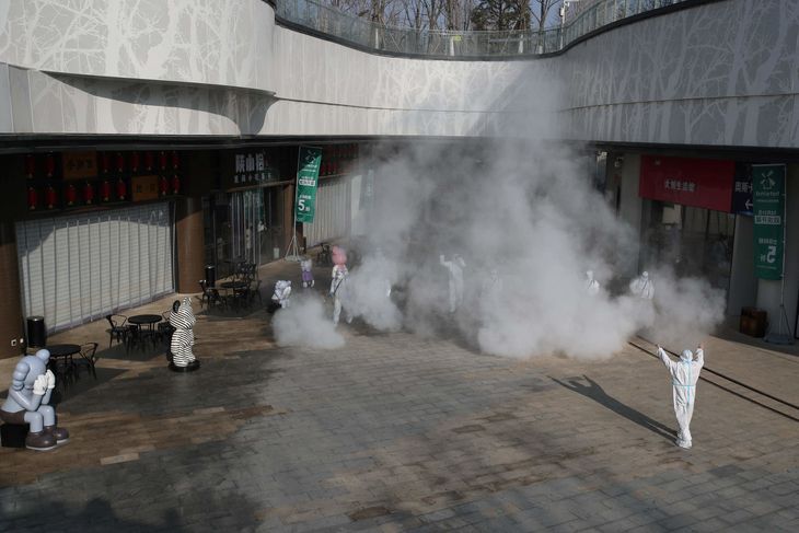 Ansatte i et shoppingcenter i Xi'an iført værnedragter sprøjter desinficerende middel. Foto: STR/Ritzau Scanpix