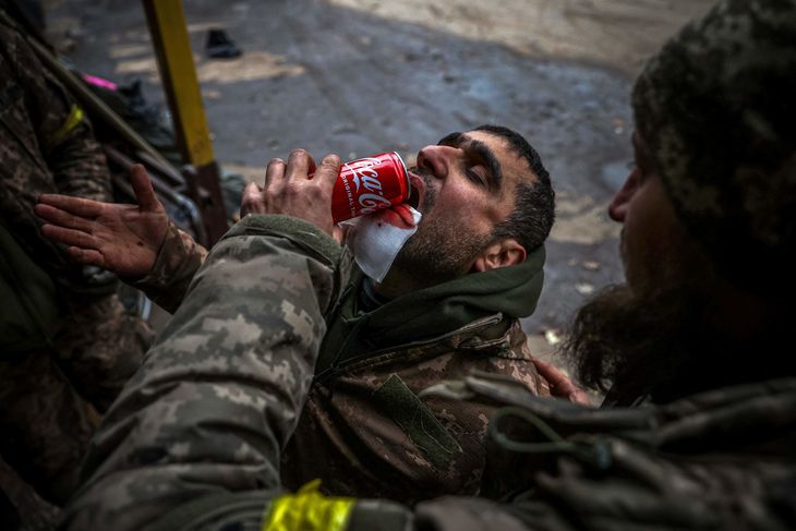 En såret ukrainsk soldat får hjælp til at drikke en cola i Bakhmut. Foto: Anatolii Stepanov/ Ritzau Scanpix