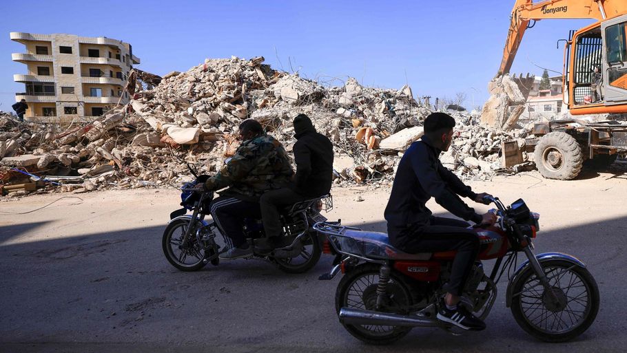 Motorcyklister kører forbi en redningsaktion i Latakia nordvest for Damaskus - et område under det syriske regimes kontrol. Mike Ryan, krisechef i Verdenssundhedsorganisationen (WHO), siger, at det er særlig vanskeligt at hjælpe i Syrien, hvor millioner allerede før skælvet levede i dyb krise - glemt af det internationale samfund. Foto: Karim Sahib/Ritzau Scanpix