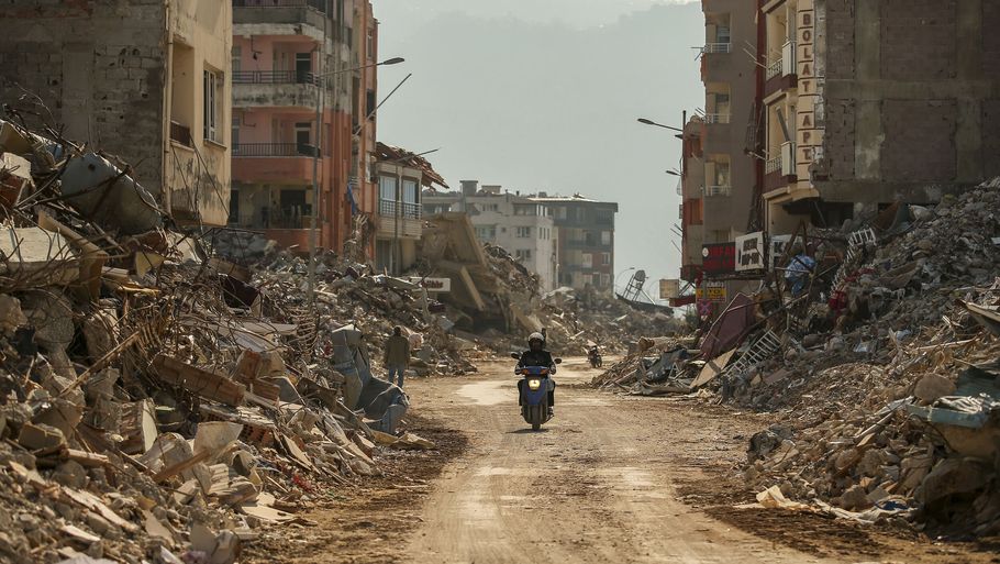 En mand kører på motorcykel mellem de ødelagte bygninger i byen Samandag i det sydlige Tyrkiet, som blev hårdt ramt af jordskælvet 6. februar. (Arkivfoto). Foto: Emrah Gurel/Ritzau Scanpix