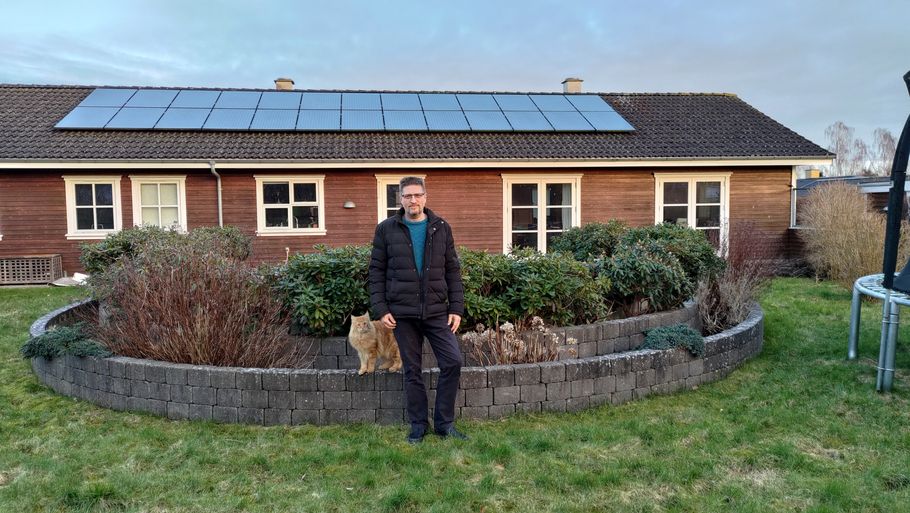 Jesper med katten Knas foran det solcelleanlæg han installerede for ti år siden. Privatfoto