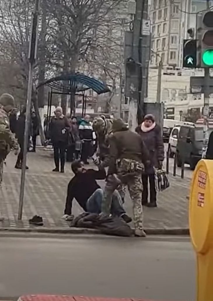 En mand kæmper ihærdigt for at komme fri af de tre ukrainske militærfolk foran et indkøbscenter i havnebyen Odesa på Panteleimonivs'ka Street. 