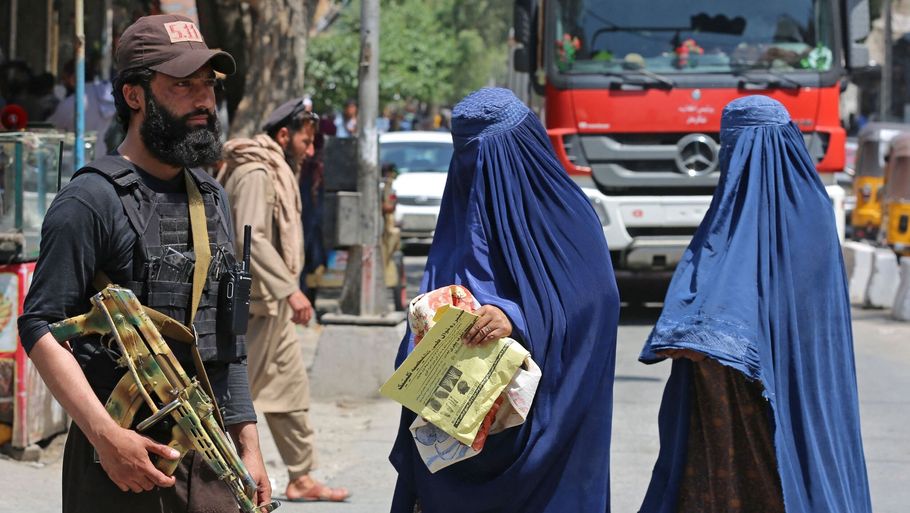 To afghanske kvinder i burka passerer forbi en talibaner i byen Jalalabad i Afghanistan søndag. Mandag er USA, Kina, Rusland, FN og flere andre samlet i Doha for at tale om Taliban og især styrets behandling af kvinder. Foto: Shafiullah Kakar/Ritzau Scanpix